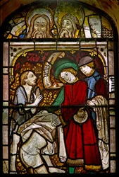 Un pannello nella finestra est che raffigura le Opere di Misericordia: vestire i nudi; anche alcune teste finemente riposizionate