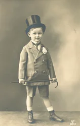 Ragazzo in abito doppiopetto, con cilindro e bastone