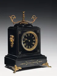 Un orologio da mensola in pietra composita nera, con decorazioni incise, con gambe, pinnacoli e raccordi in ottone dorato, di Jausions di Pau, Francia