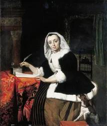 Una signora elegante che scrive alla sua scrivania, con un cane accanto