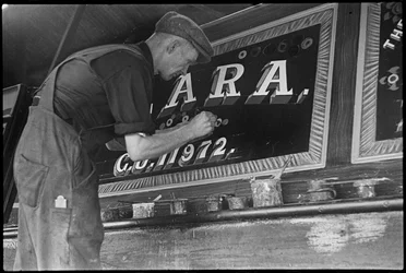 Frank Jones, al lavoro per dipingere il pannello nominativo di una chiatta, XX secolo (foto)