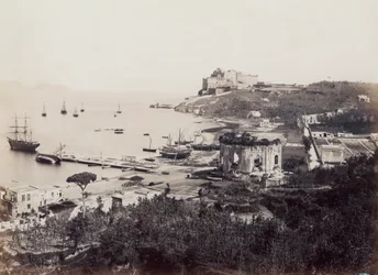 Panorama del pittoresco Golfo di Baia (Napoli), punteggiato di barche a vela. In primo piano, di fronte al piccolo molo, si trova il Tempio di Venere. Sullo sfondo, arroccato su un promontorio, si trova il Castello del Viceré del XVI secolo