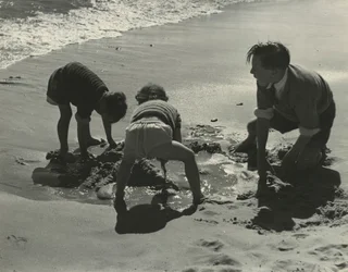 Tre bambini che giocano con la sabbia in spiaggia
