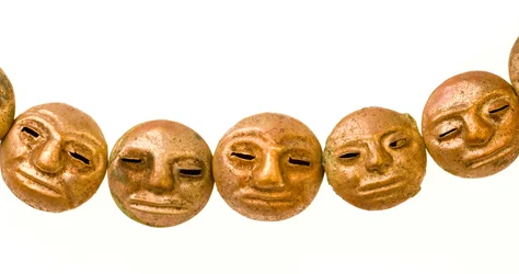 Una collana trovata intorno al collo della mummia con piccoli volti d