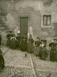 Donne e bambini che indossano abiti tradizionali sui gradini che portano alla casa, Abruzzo, Italia