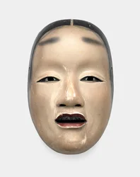 Una maschera di legno con base di gofun, dipinta con sumi per i capelli, gli occhi e i denti e rosso per le labbra