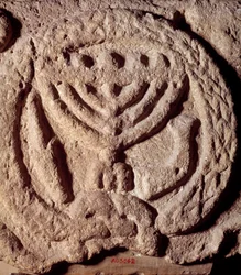 Giudaismo: elemento architettonico in basalto di una sinagoga decorato con un candelabro a sette braccia (Menorah), palma e tromba. Da Transgiordania. Circa 100 d.C. Parigi, Museo del Louvre