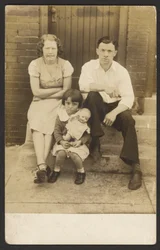 [Famiglia con bambola sul portico]