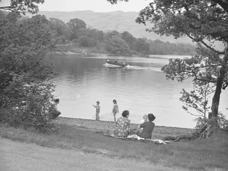 Una famiglia si diverte vicino a un lago, barca sul lago, montagne sullo sfondo