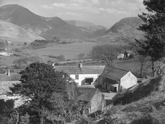 Una veduta di quella che sembra essere una fattoria in primo piano e un lago e delle colline sullo sfondo.