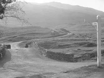 Vista della strada che passa sopra il passo di Hardknott con un cartello che indica la direzione di Hardknott