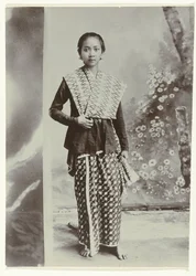 Ritratto in studio di una giovane donna giavanese in un sarong con motivo batik e una camicia a quadretti