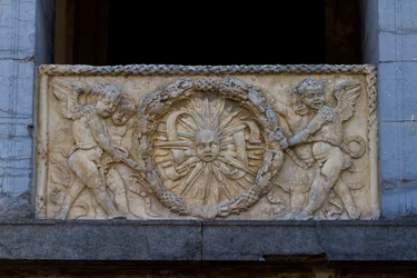 Piatto di balaustra con sole raggiante in ghirlanda, bassorilievo sulla facciata della chiesa di San Sebastiano