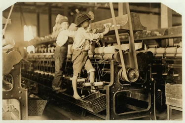 Ragazzini che scalano il telaio per riparare fili rotti e sostituire bobine vuote al Bibb Mill, Macon, Georgia, 1909