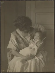 [Florence tiene il bambino sulla sedia a dondolo]