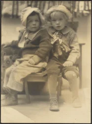 [Due bambini che condividono la sedia]