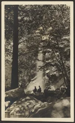 [Due figure vicino a una cascata nel bosco].