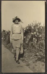 [Donna che cammina lungo la staccionata con i fiori]