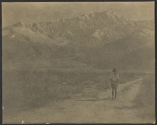 [Donna che cammina sul sentiero verso le montagne]