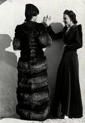 Due modelle presentano creazioni della casa di moda italiana "Dragoni". Una modella vista di spalle indossa un cappotto di volpe argentata. L