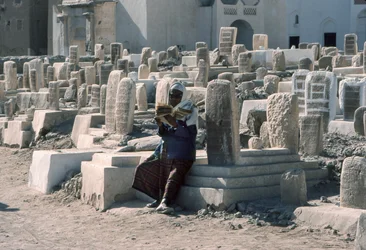 Uomo yemenita recita il Corano nel cimitero con tombe a Sayun, Hadramawt, Yemen del Sud.