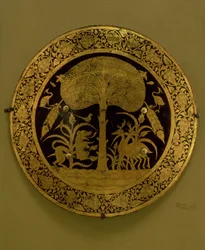 Piatto con bordo di fiori stilizzati che circondano una scena di animali esotici sotto un albero (bronzo dorato)