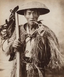 Coolie giapponese (lavoratore agricolo) con un cappello per proteggersi dalla pioggia intensa nei campi di riso (foto in bianco e nero)