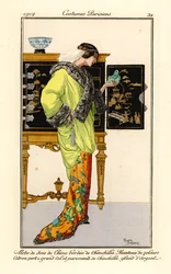 Donna in abito di seta con finiture in cincillà, mantello in velluto verde limone con colletto e polsini in cincillà, tiene in mano un buddha di giada. Sullo sfondo un gabinetto cinese. Abito di seta di Cina con bordo di cincillà, mantello di velluto verde