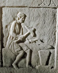 Arte romana: dettaglio di una stele che raffigura un fabbro che colpisce il metallo su un
