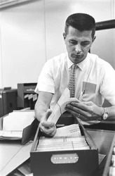 Operatore informatico Don Murray lavora con un primo computer digitale IBM che utilizza schede perforate