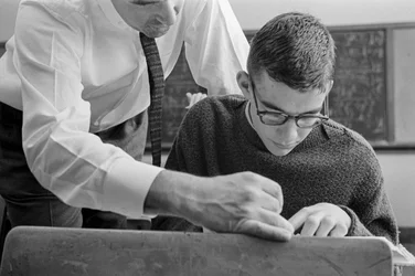 Insegnante che aiuta uno studente con il testo alla James A. Garfield High School