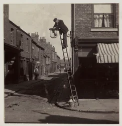 Uomo che pulisce un lampione a gas, circa 1905