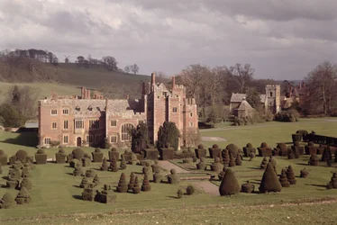 Esterno che mostra il giardino topiario e la chiesa oltre, Compton Wynyates, Warwickshire, fine XV-inizio XVI secolo