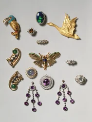 Selezione di gioielli: orecchini a lampadario con ametista e diamanti; spilla con zaffiro stellato cabochon e diamanti; anello con opale nero; spilla o pendente con ametista e diamanti; spilla a clip a forma di cigno volante in oro; Tiff