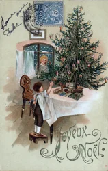 Cartolina di auguri di Natale: un bambino davanti a un albero di Natale posa su un tavolo, osservato da un angelo alla finestra - Cartolina datata 1905