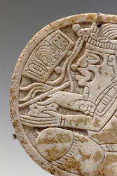 (dettaglio) da un tondo di conchiglia maya, raffigurante uno scriba a gambe incrociate con penna in mano