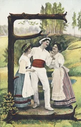 E : Un uomo vestito di bianco e rosso si trova in piedi tra due donne con gonna, corpetto e grembiule. Ambiente campestre - Alfabeto personaggi Rif Th. E., L. Theochrom - Serie 994. Theodor Eisman, editore, Lipsia