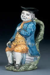 Brocca Toby con volto e mani di colore manganese pallido, che tiene una brocca globulare vuota di colore buff in giacca e pantaloni blu lavato, e gilet verde, c.1800