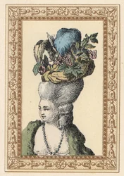 Donna con acconciatura raccolta con cappello decorato con uva e piume chiamato Cappello Racy in un parco inglese