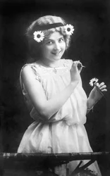 Donna che strappa petali da un fiore: "Mi ama. Non mi ama. Mi ama..." Fotografia intorno al 1912