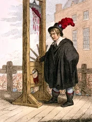 George Tierney vestito da boia accanto a una ghigliottina