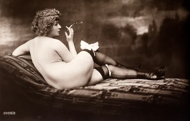 Ritratto di una giovane donna che posa nuda, di spalle, mentre fuma una sigaretta