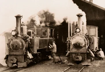 Due locomotive a vapore in manutenzione da parte di due operai