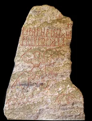 Una stele con iscrizioni runiche che rappresentano un cavaliere vichingo con un cane (pietra)