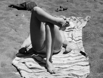 Gambe femminili su una spiaggia, 1960 circa (foto b/n)
