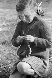 Bambina che crea una collana di margherite