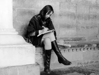 Giovane donna che scrive sotto la Loggia del Lanzi a Firenze, 1965 circa (foto b/n)