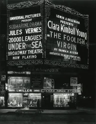 1554 Broadway alla 46th Street, I. Miller Shoes; James Drug Store, e grandi insegne per film illuminate sopra.