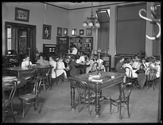 Bambini che leggono nella sala di lettura di una filiale non identificata della Queens Borough Public Library, c.1910