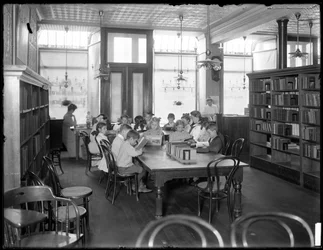 Bambini che leggono nella sala di lettura di una filiale non identificata della Biblioteca Pubblica del Queens, c.1910